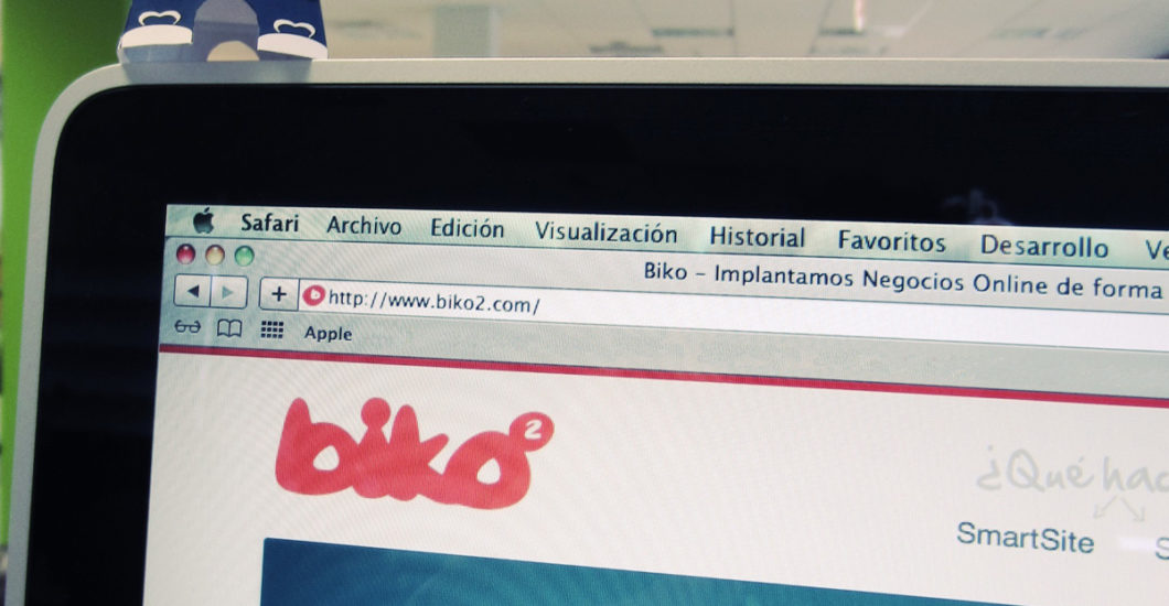 iMac mostrando la nueva web de Biko, con el consultor en papel encima